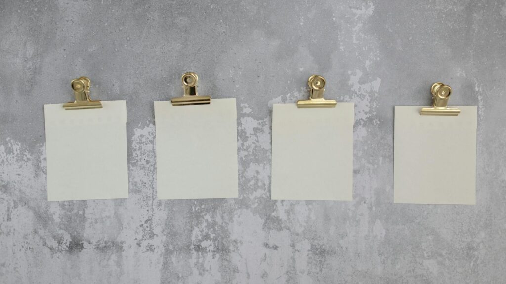 Blank stickers for notes attached with gold holders and hung on gray wall